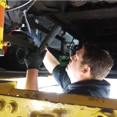 Photo of a Synchro Technician inspecting the undercarriage of an HGV over the inspection pit